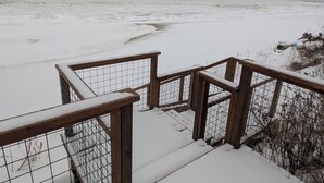 Una escalera de madera cubierta de nieve que da a una playa con vista al océano.
