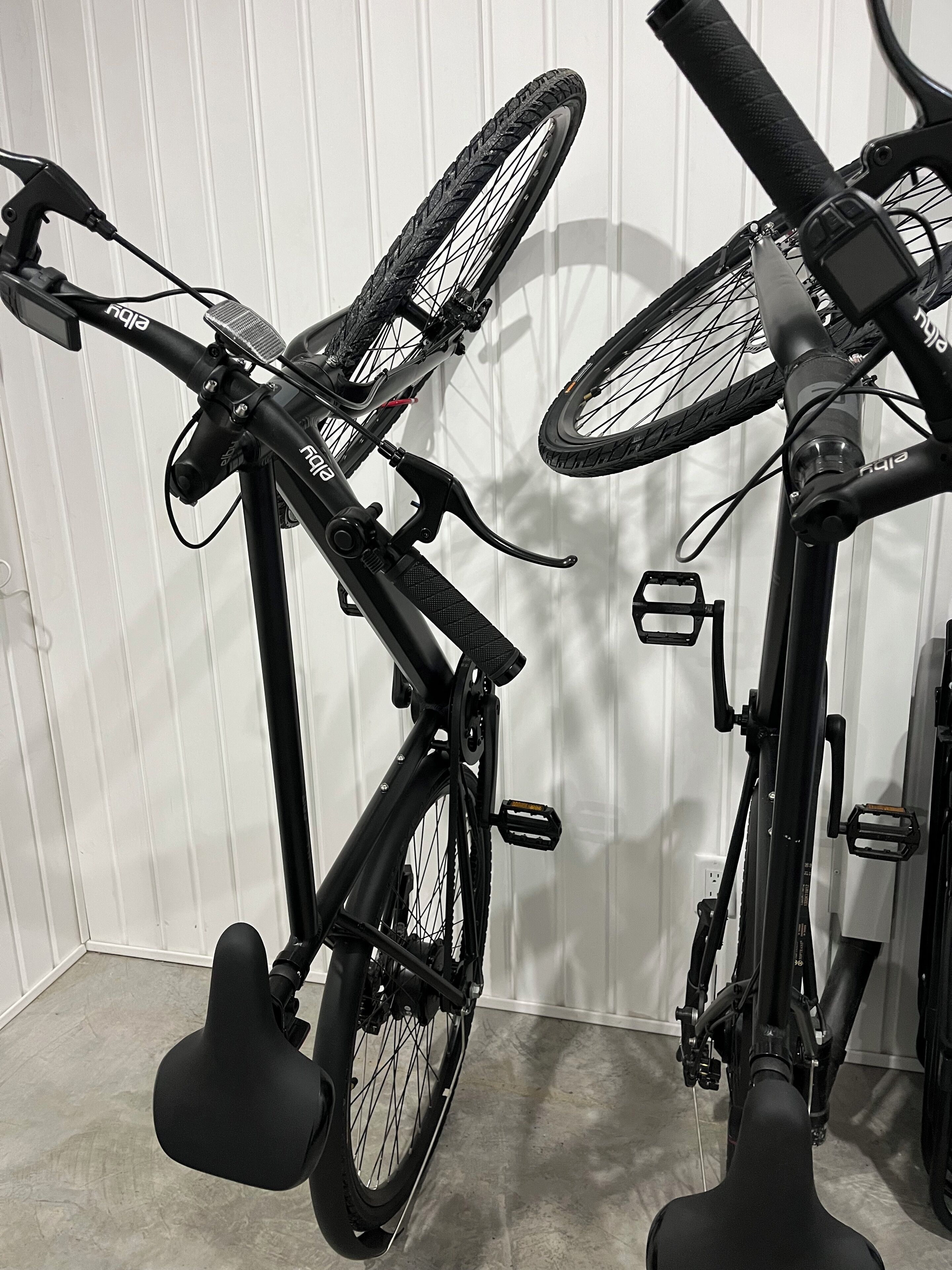 Dos bicicletas apoyadas contra una pared blanca.