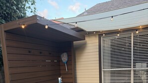 Un jacuzzi con escalones, una pérgola de madera y una guirnalda de luces.