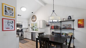Una cocina moderna con armarios blancos, una mesa de comedor con sillas y una araña.