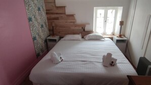 Une chambre d’hôtel avec un lit, une table de chevet, une lampe et une fenêtre avec des rideaux.