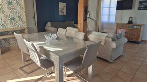 Un coin repas avec une table en verre, des chaises blanches, un buffet en bois et un mur bleu.