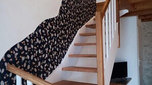 Een houten trap met witte leuningen en een donker geweven stof over de handrail.