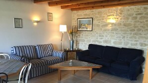 A living room with a striped sofa, a dark sofa, a tiled floor, a wooden coffee table, and a lamp. - House 14 sleeps 5 2 bathrooms (Ternant)