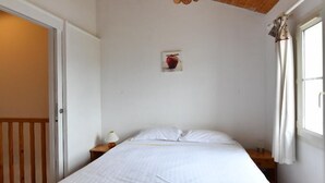A bedroom with a wooden ceiling, a bed with white bedding, a nightstand, a wall-mounted lamp, and a window with curtains. - House 14 sleeps 5 2 bathrooms (Ternant)