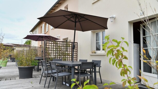 An outdoor patio with a table and chairs, two umbrellas, and potted plants. - House 14 sleeps 5 2 bathrooms (Ternant)