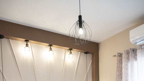 A modern bedroom with a large bed, a wooden headboard, and a unique light fixture. - Aurora Breeze Trikala Town (Trikala)