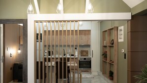 A modern kitchen with wooden cabinets, a dining area with a table and chairs, and pendant lighting. - Aurora Breeze Trikala Town (Trikala)