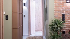 A hallway with a marble floor, a brown rug, a potted plant, and a brick wall. - Aurora Breeze Trikala Town (Trikala)
