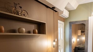 A modern living room with a sectional sofa, a shelf with decorative items, and a view into a connected room. - Aurora Breeze Trikala Town (Trikala)