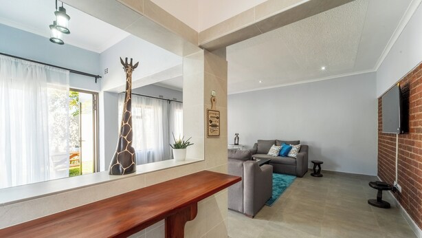 Un soggiorno moderno con un divano, un tavolino e una TV montata su un muro in mattoni.