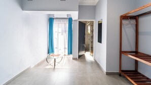 Una stanza con un letto, una mensola in legno, un tavolo e una finestra con tende.