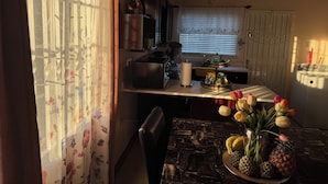 Eine Küche mit Esstisch, Kühlschrank und einem Fenster mit Jalousien.
