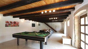 Een pooltafel in een ruimte met een houten plafond en een trap die naar een ander niveau leidt.