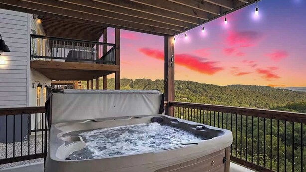 Een bubbelbad op een balkon met een prachtig uitzicht op heuvels en een zonsondergang.