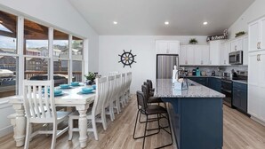 Een moderne keuken met witte kasten, een centraal eiland en een eethoek met witte stoelen.