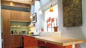 Una cocina moderna con armarios de madera, una isla grande con taburetes, un horno empotrado y una ventana con plantas en macetas.