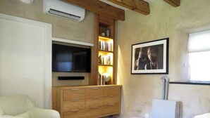 Una sala de estar con televisor de pantalla plana, un mueble de madera, estanterías y un cuadro en la pared.