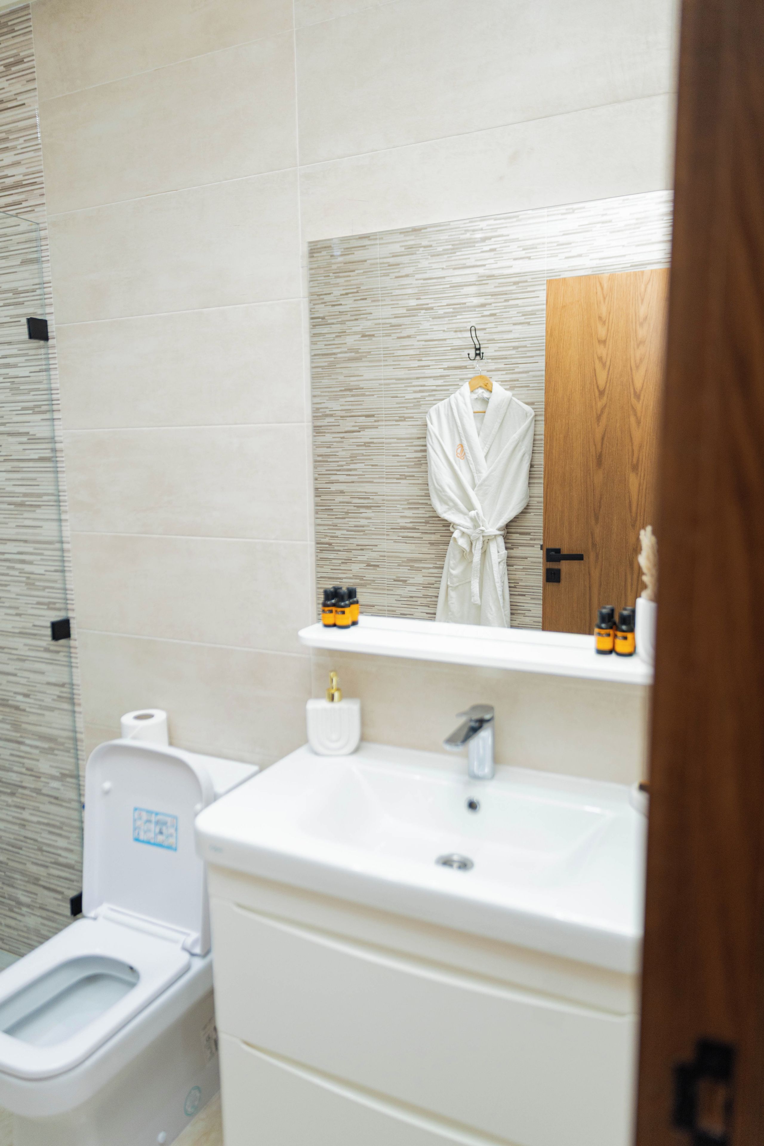 A bathroom with a toilet, sink, and a mirror above the sink.