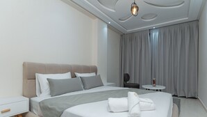 A modern hotel room with a large bed, a bedside table, a small round table, and a ceiling light fixture. - Appart Hotel Golden Sky Home (Beni Mellal)
