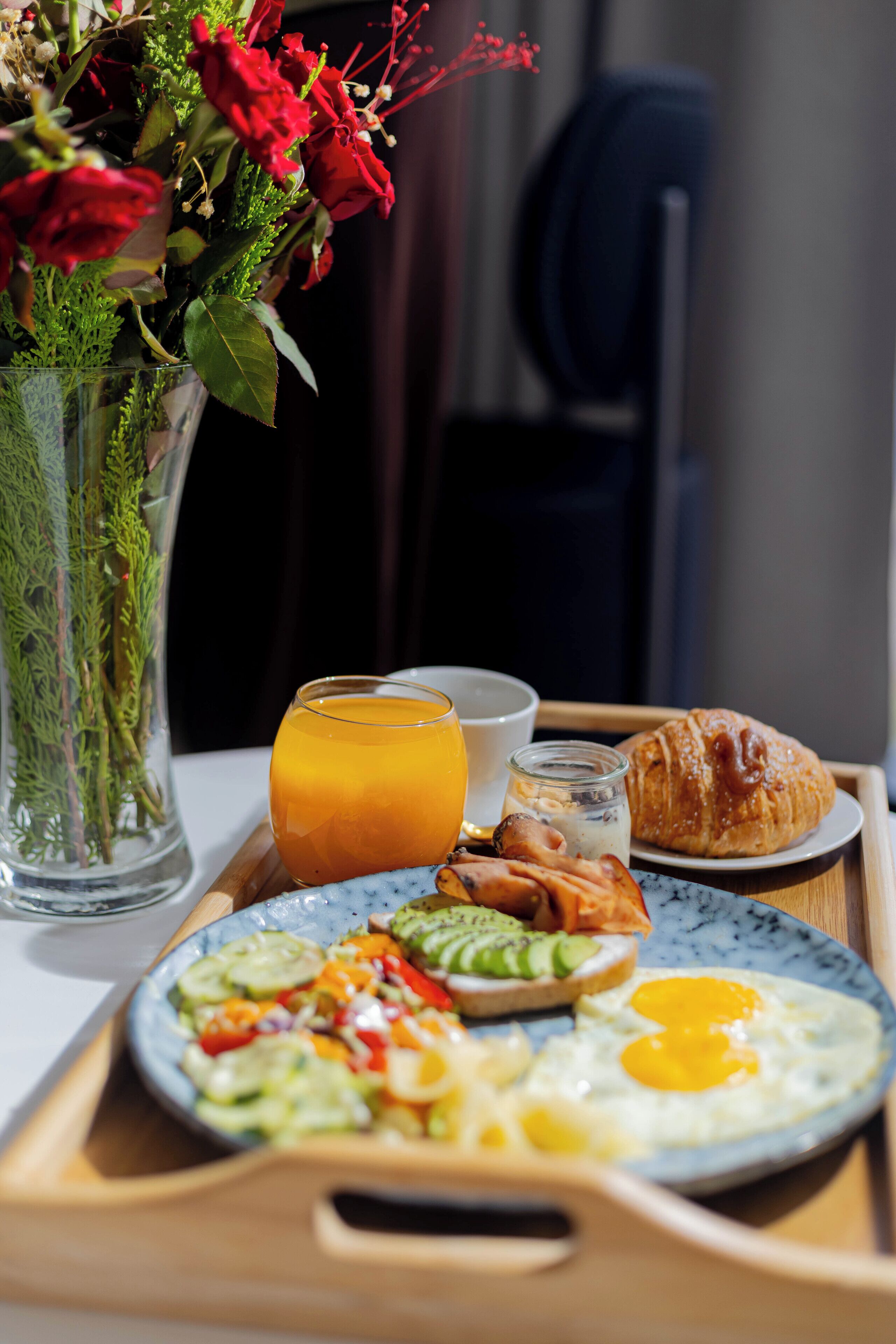 Bandeja de desayuno con huevos, tostadas, aguacate y un croissant.