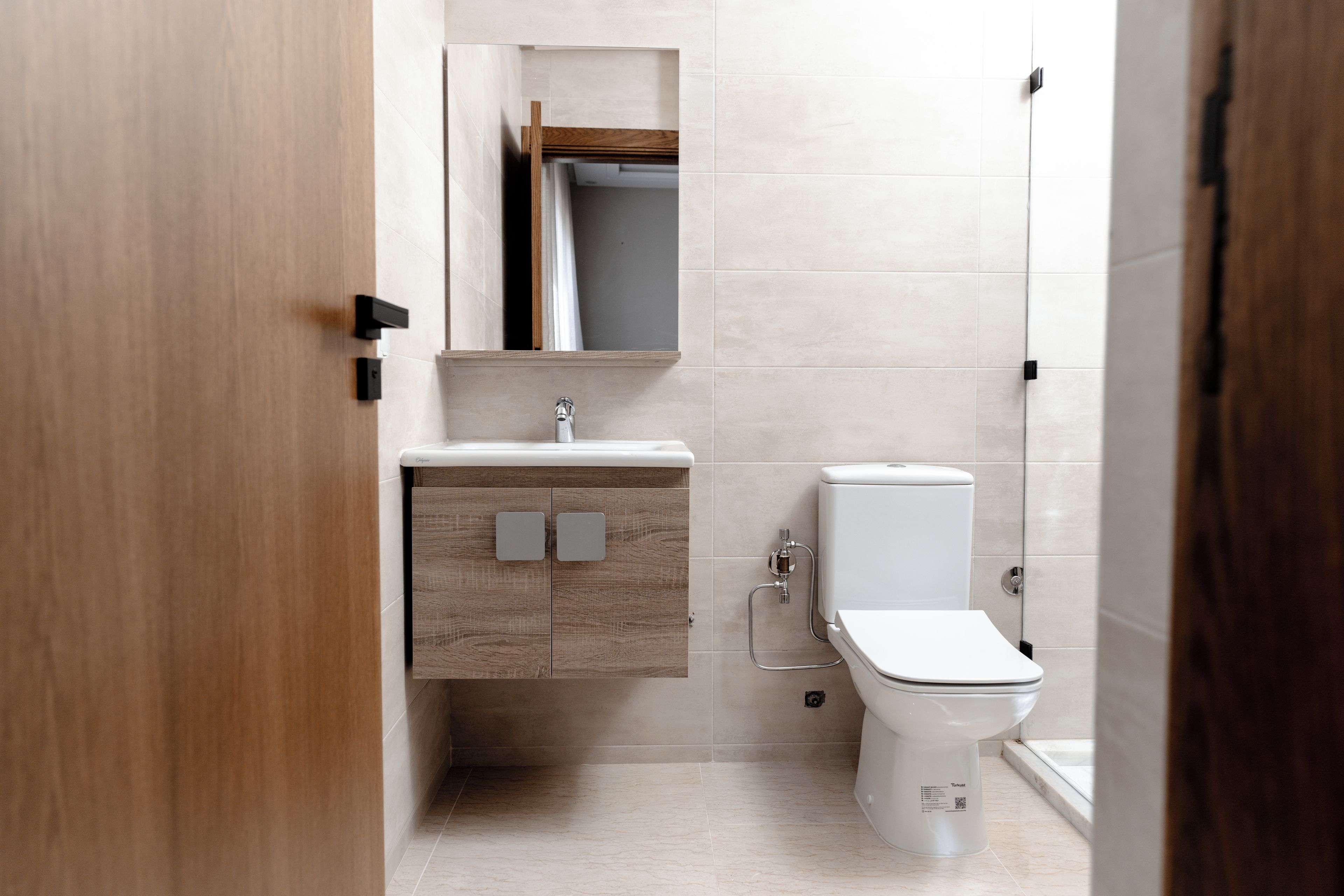 Un baño moderno con tocador de madera, inodoro y zona de ducha.