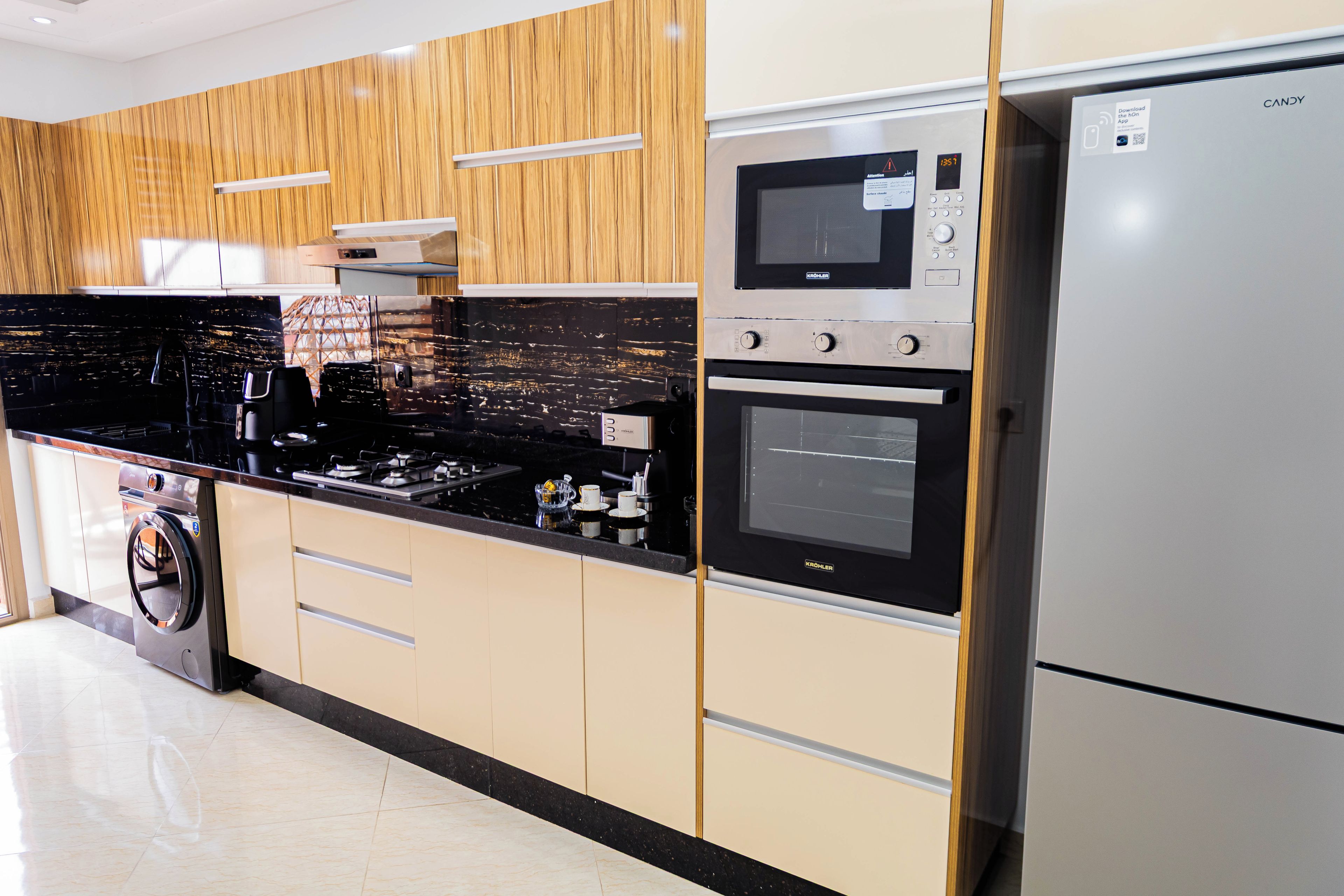 Cocina moderna con lavadora integrada, refrigerador de acero inoxidable y microondas.