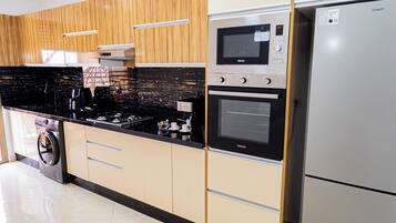 Cocina moderna con lavadora integrada, refrigerador de acero inoxidable y microondas.