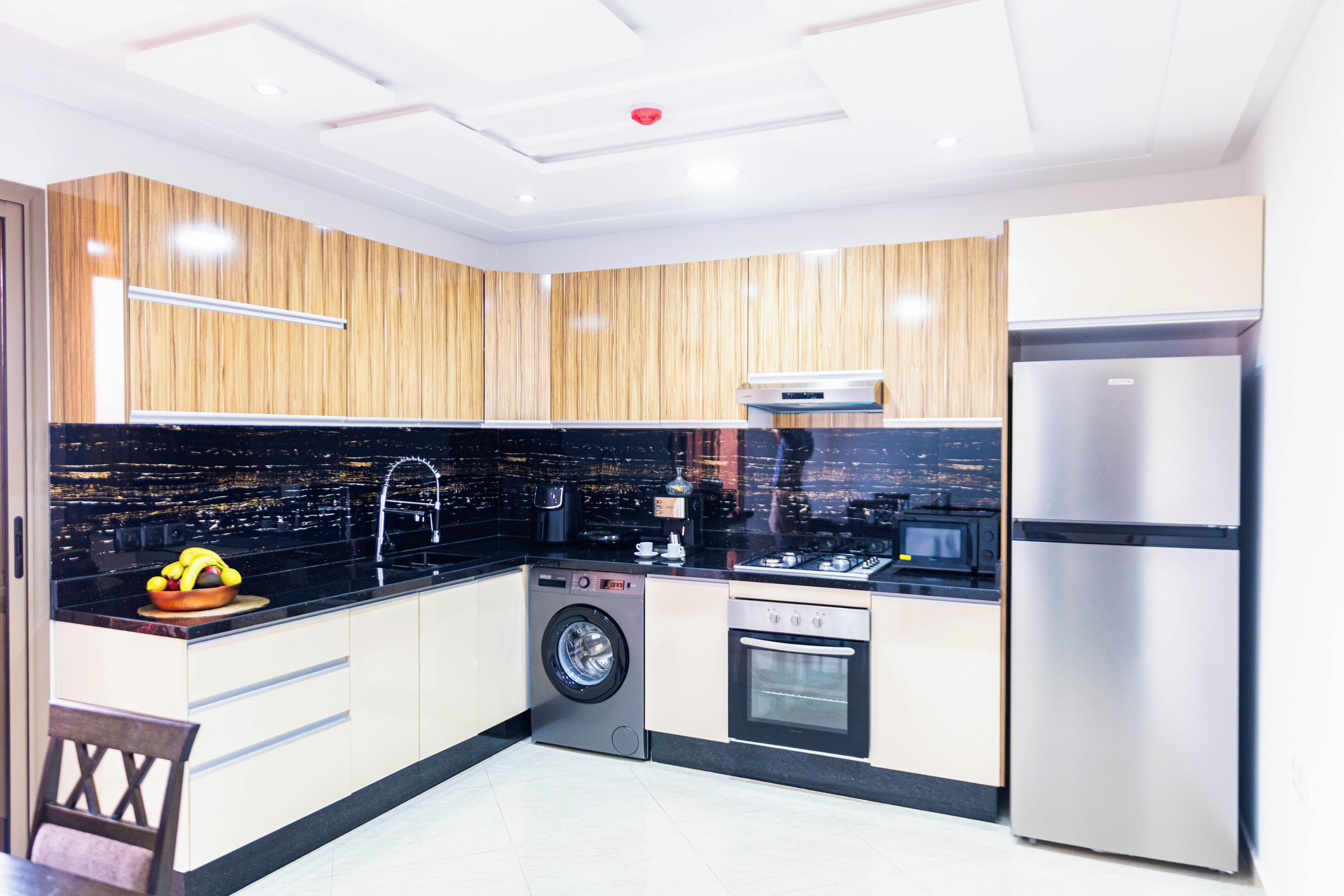 A modern kitchen with a built-in washing machine, a refrigerator, and a coffee maker.