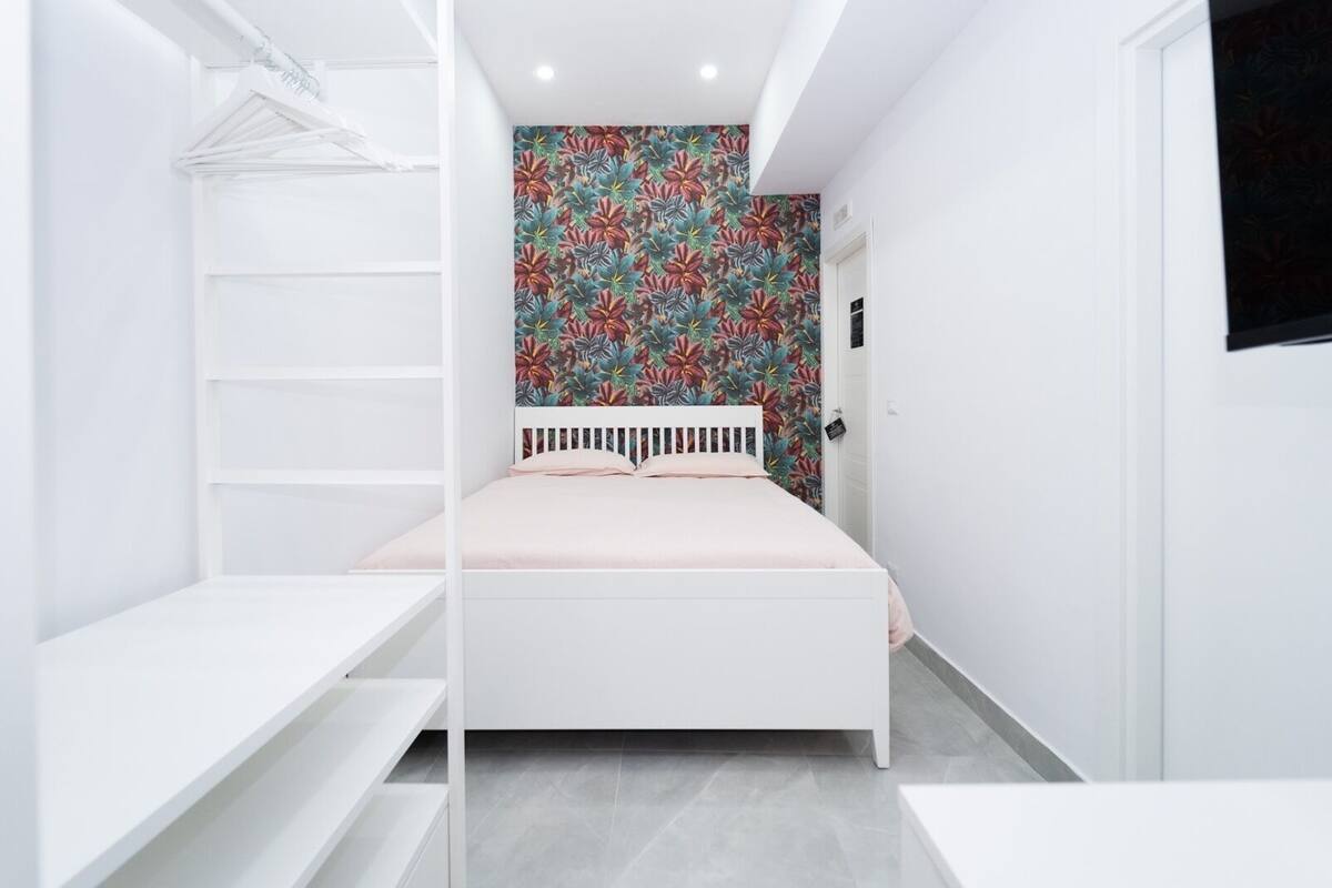 A bedroom with a bed, a wardrobe, and a floral wallpaper.