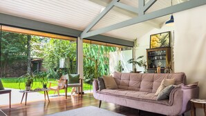 Ein geräumiges Wohnzimmer mit großem Fenster, einer gepolsterten Couch und einem Holztisch.