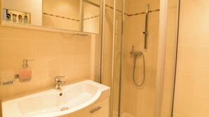A bathroom with a glass-enclosed shower, a sink with a soap dispenser, and a mirror above the sink. - The Cristal apartment house is situated in a quiet, sunny and central location (Leukerbad)