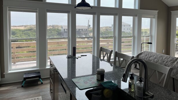 Una cocina con amplios ventanales, encimera de granito y vistas a la playa.