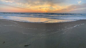 Una playa con olas y un atardecer.