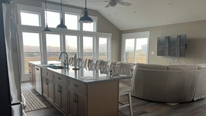 Una cocina moderna con una isla grande, armarios empotrados e iluminación colgante. Una ventana amplia ofrece vistas al exterior.