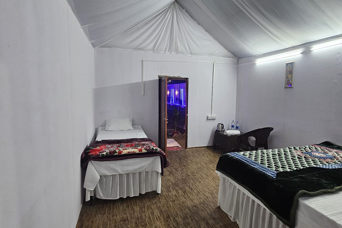 A tented room with two beds, a desk, and a chair.