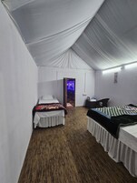 A tented room with two beds, a desk, and a chair.