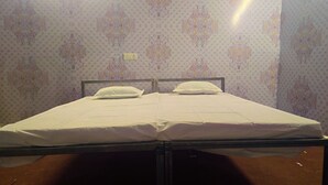 Een tweepersoonsbed met witte lakens in een kamer met behang met een patroon.