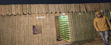 A bamboo structure with a small window and a striped curtain.