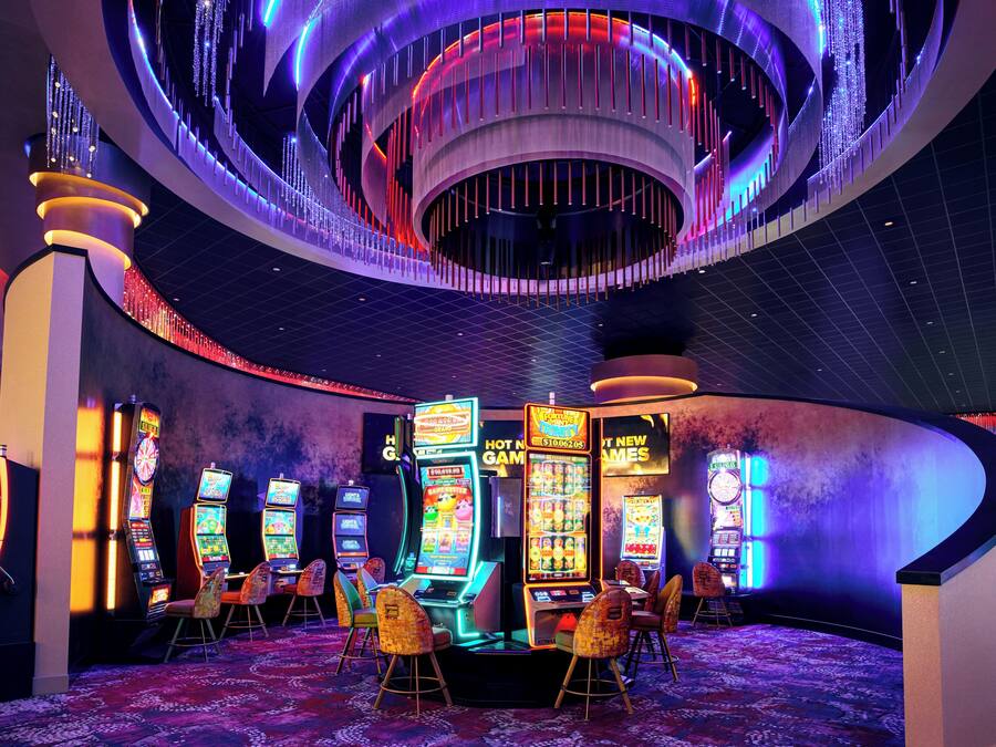 A casino with slot machines, a roulette wheel, and a neon-lit ceiling.