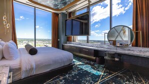A spacious room with a large bed, a TV, a mirror, and a view of the city. - Wind Creek Southland Casino and Hotel (Hazel Crest)