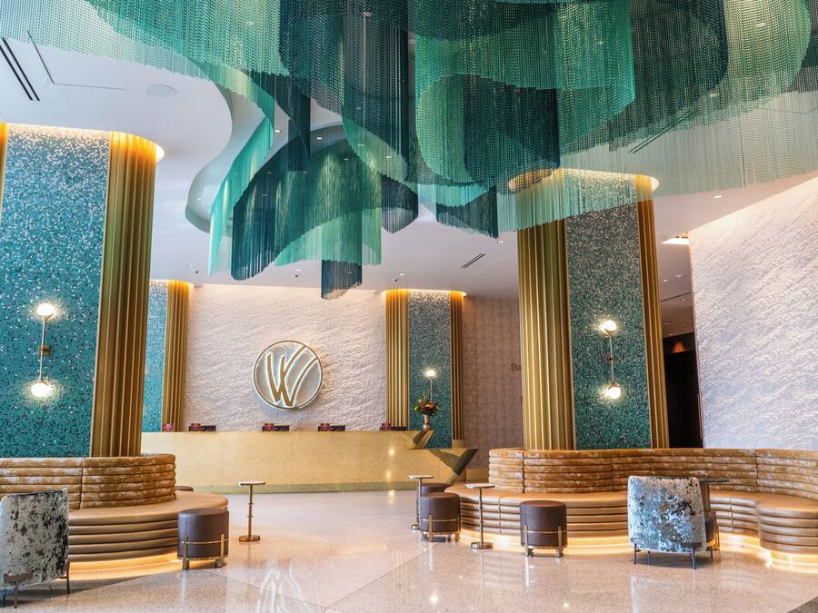 A modern lobby with a central reception desk, seating areas, and decorative lighting.