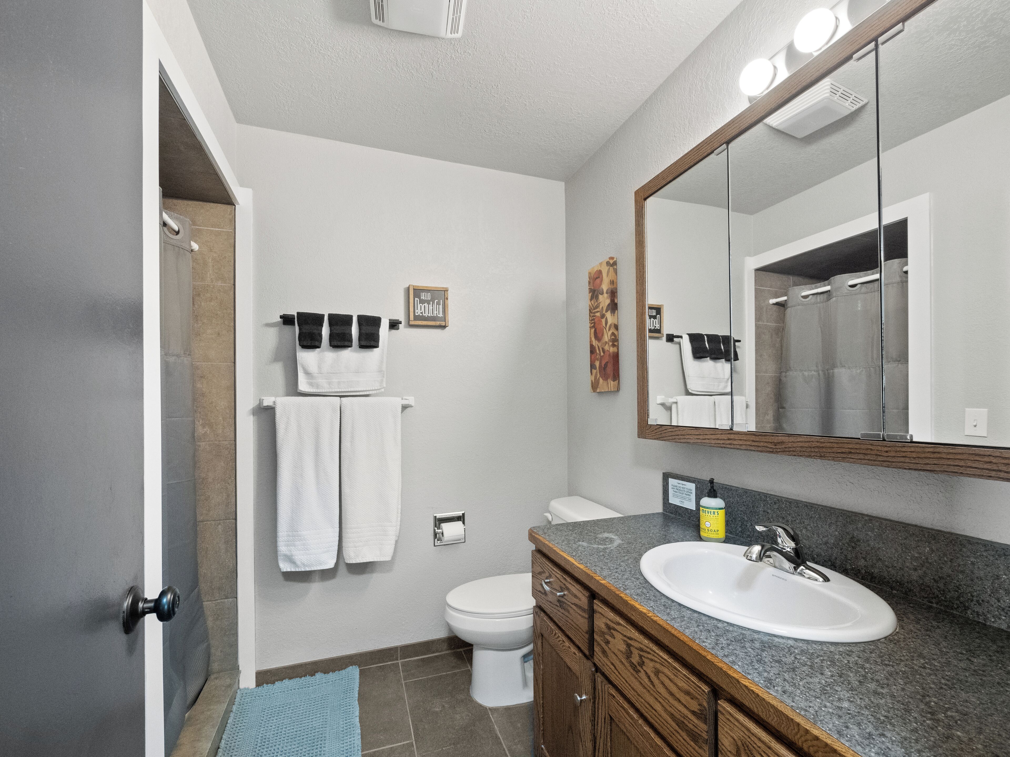 Une salle de bain avec un lavabo blanc, un miroir, des toilettes et un porte-serviettes.