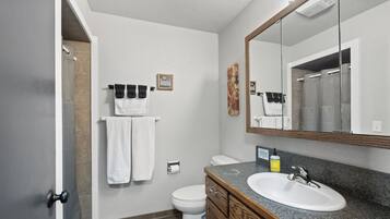 Une salle de bain avec un lavabo blanc, un miroir, des toilettes et un porte-serviettes.