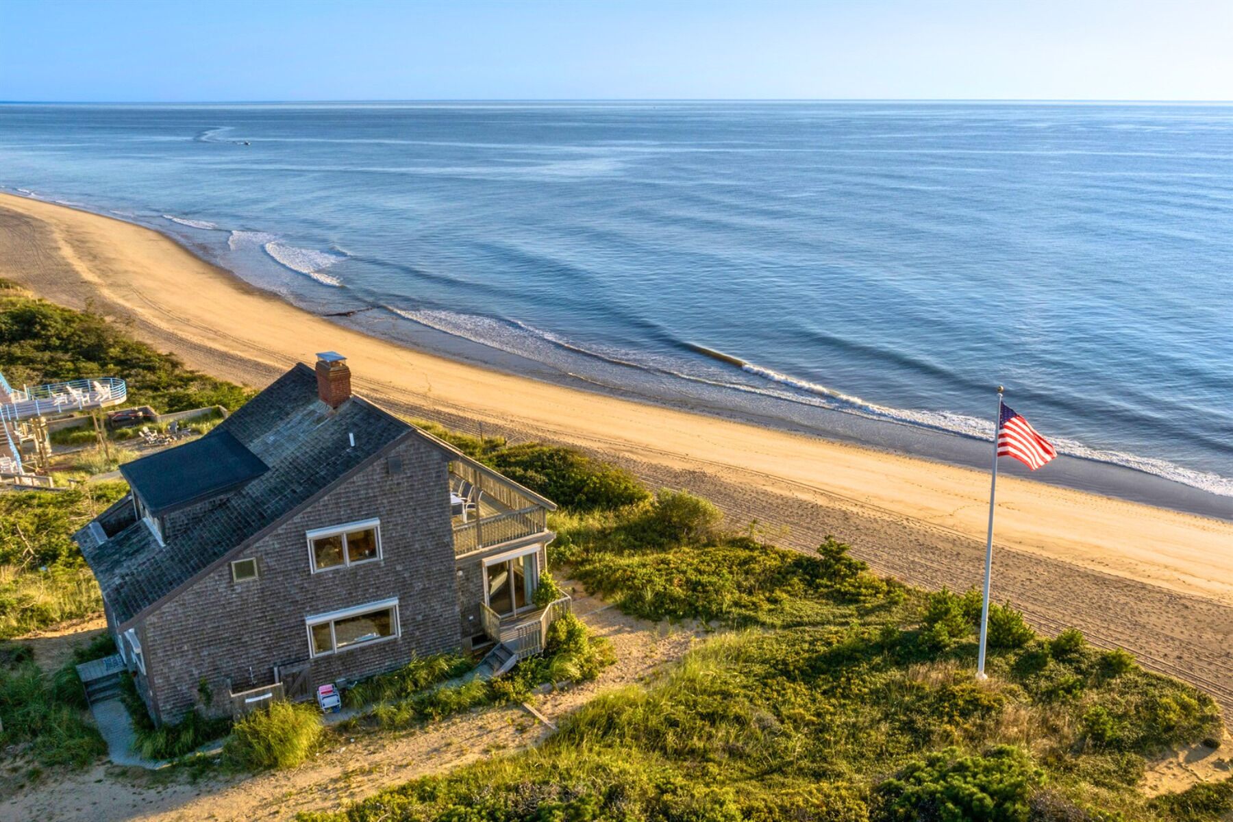 Une propriété située en bord de mer, comprenant une maison, un drapeau et une vue sur l’océan.