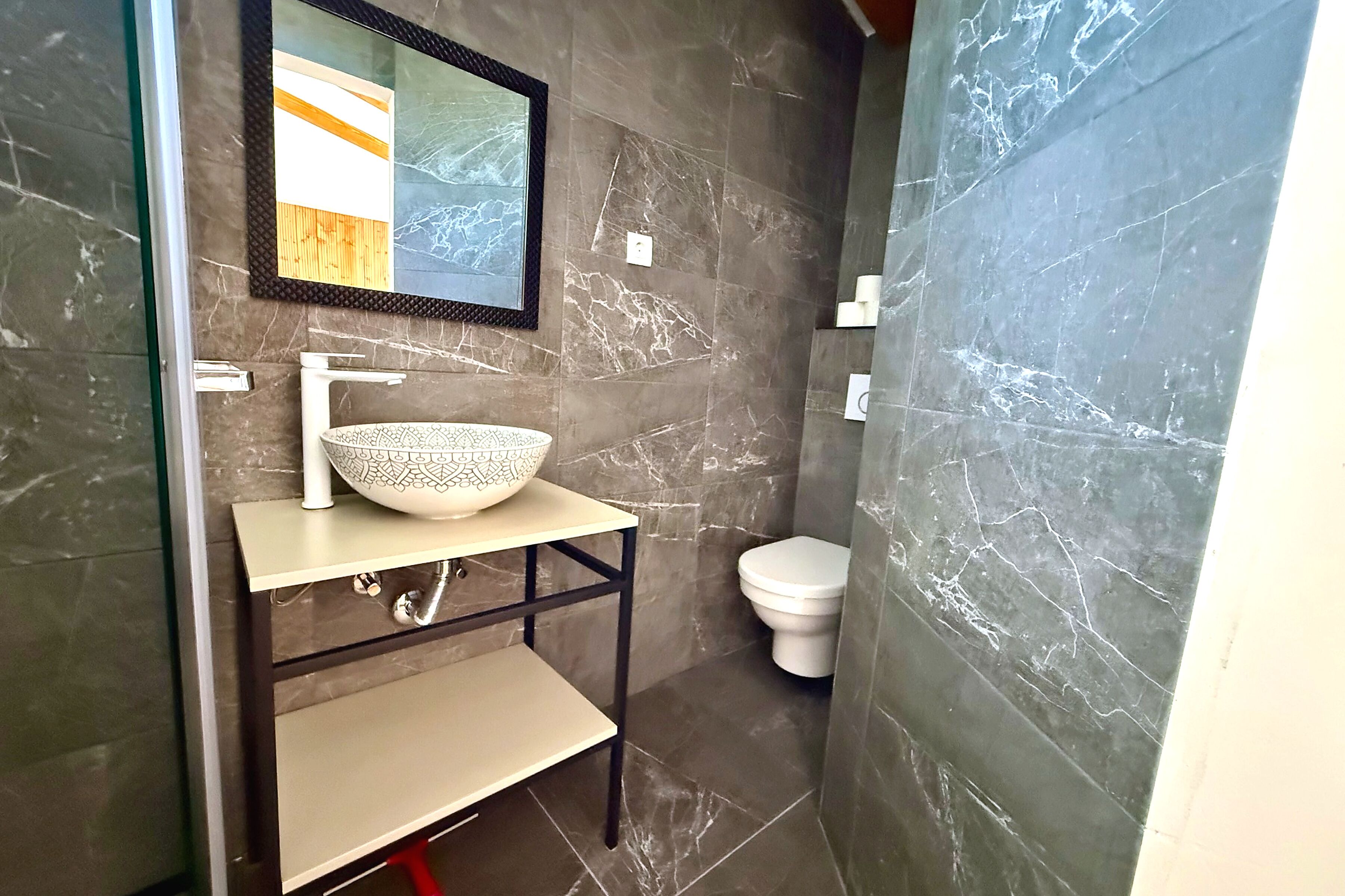 A bathroom with a marble sink, a mirror, and a toilet.