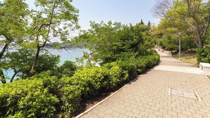 A paved pathway lined with green shrubs and trees, leading towards a body of water. - Nedia Retreat - Private Pool & Stunning Sea View (Mlini)