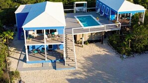 Una propiedad frente al mar de dos plantas con piscina, mobiliario exterior y un patio cubierto.