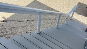 Una escalera de madera con barandilla de metal que lleva a una terraza.