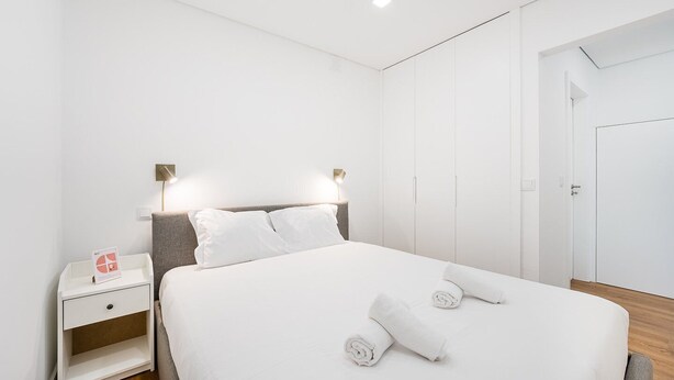 A modern bedroom with a large bed, a bedside table, a nightstand, and a wardrobe. - GuestReady - Restful Getaway in Matosinhos (Matosinhos)